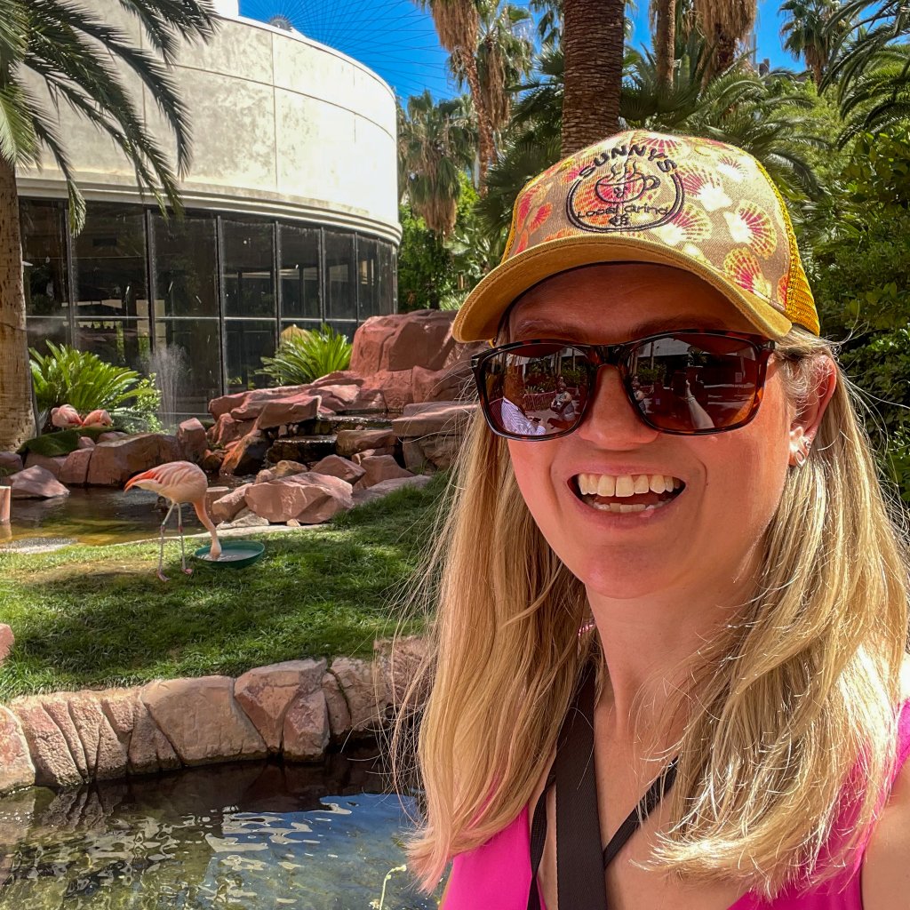 a women taking a selfie next to flamingos 