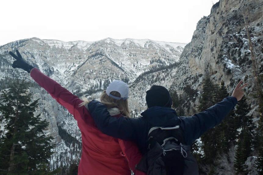 2 people at the top of a snow topped mountain