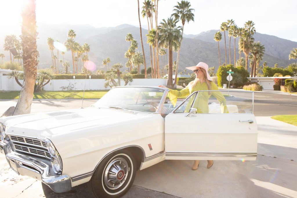 a women standing next to an antique car in Palm Springsa