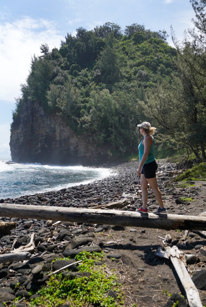 a women walking across a log on the beach