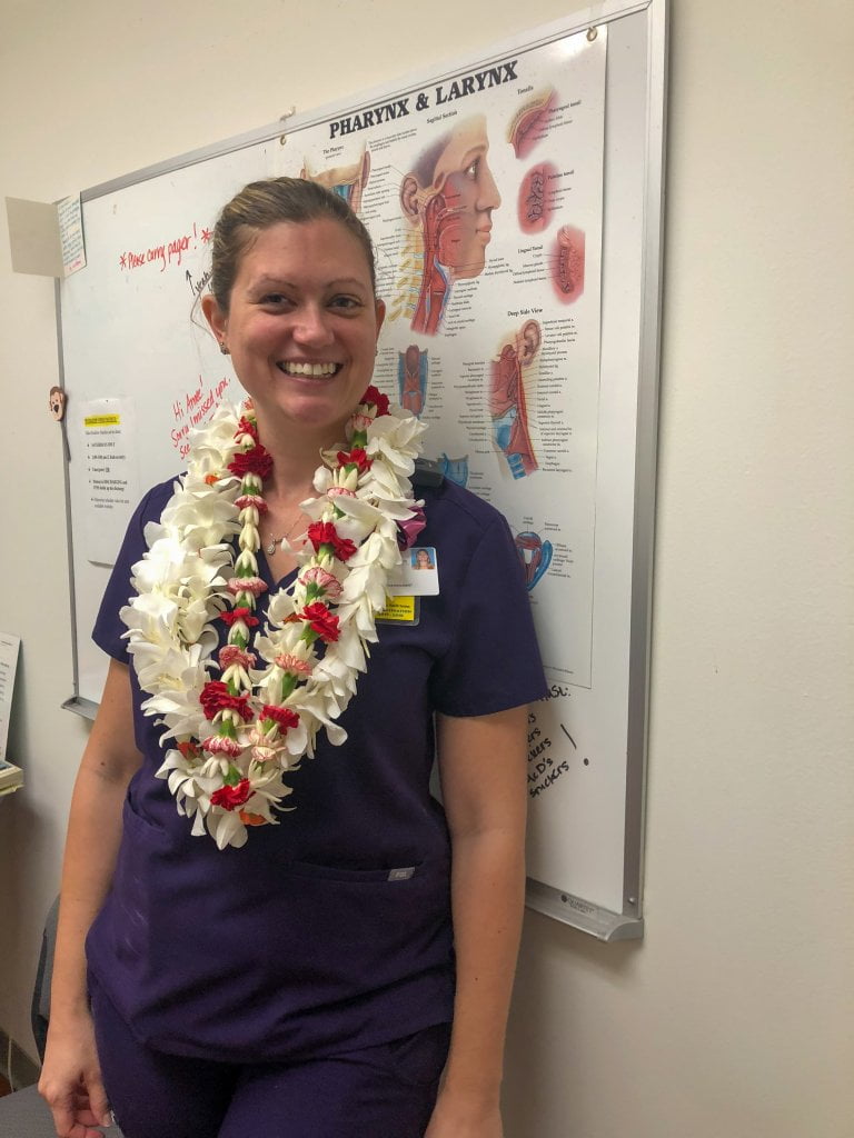 a women wearing scrubs and a bunch of leis in a hospital office