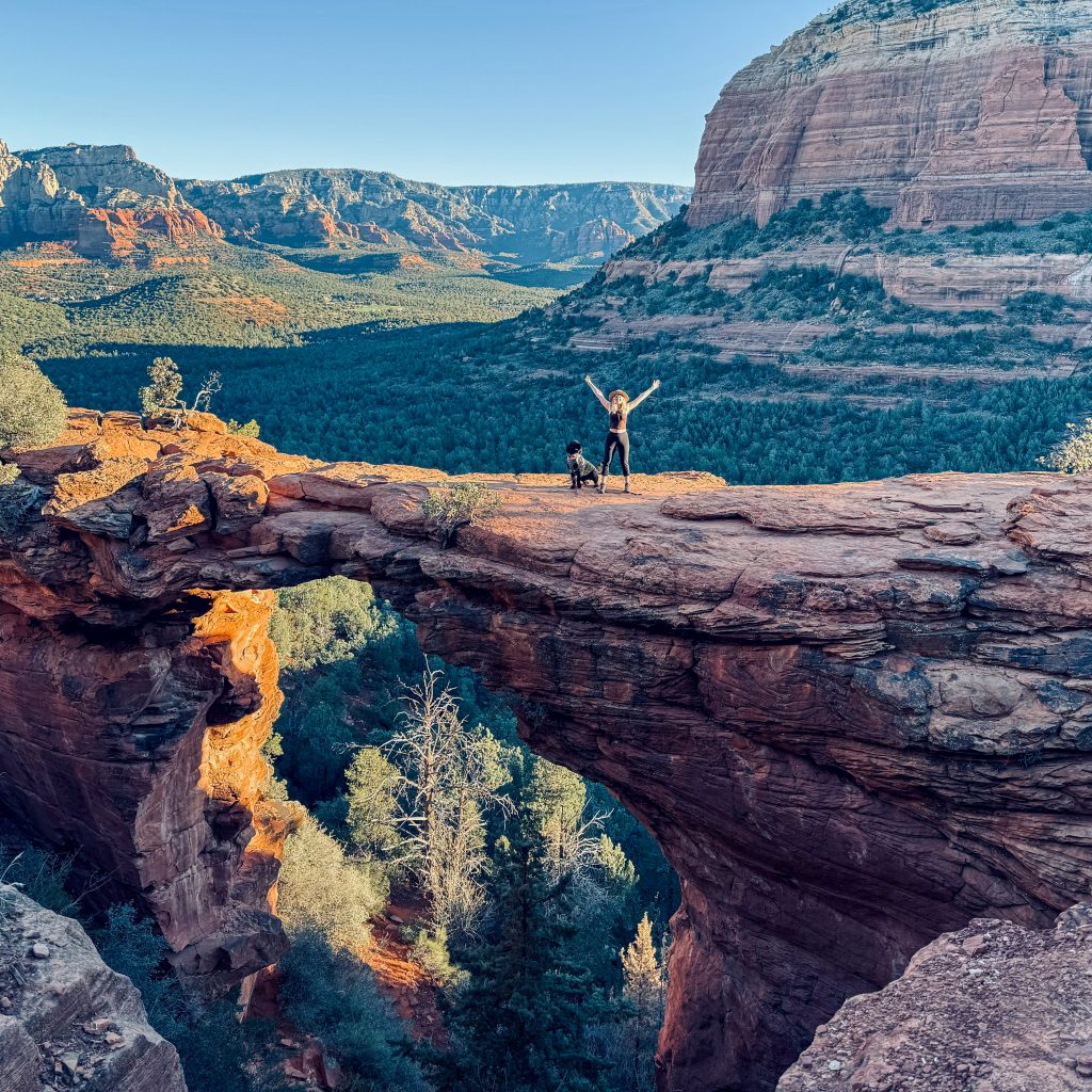 a woman standing on Devil's Bridge in Sedona with a dog