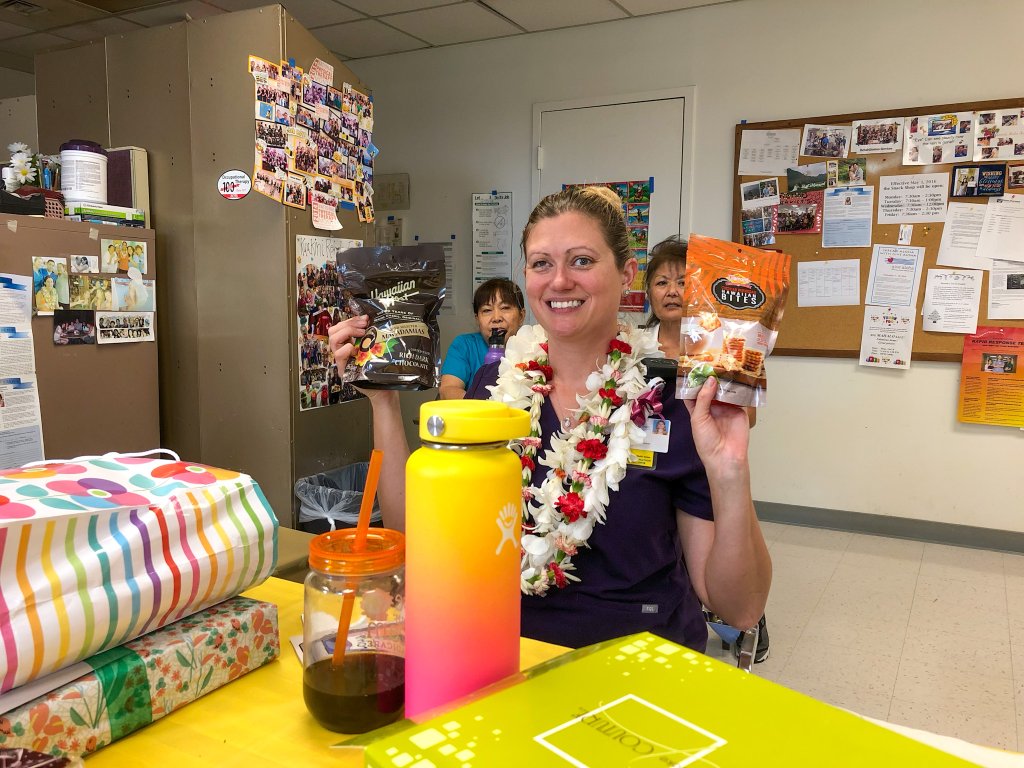 a women wearing scrubs and lei's getting gifts a