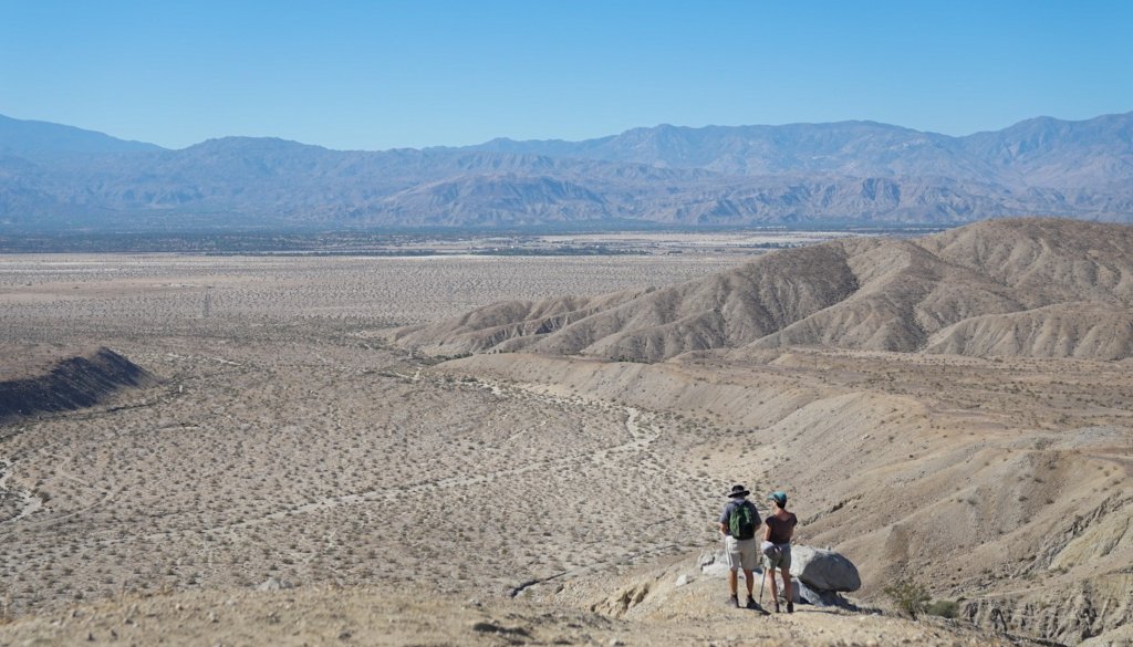 2 hikers standing at the edge of a cliff 