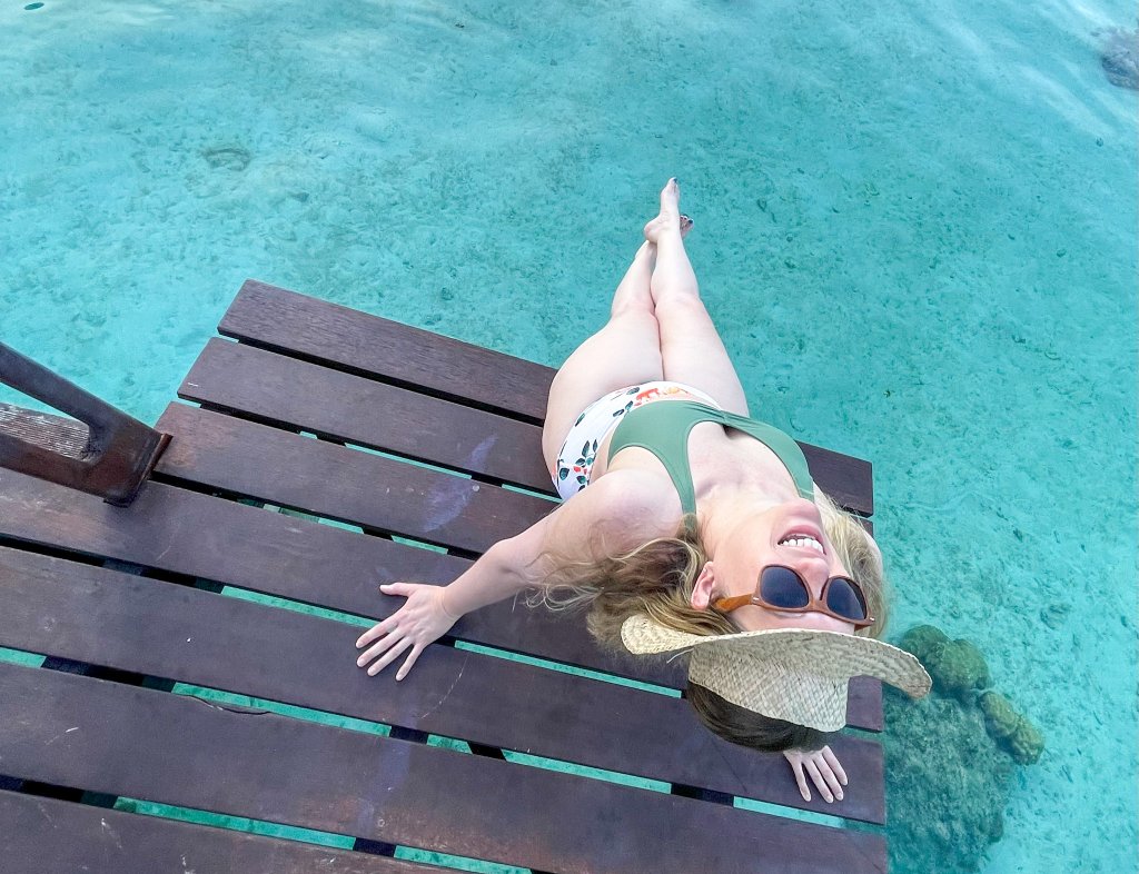 a women in a bathing suit sitting on a dock