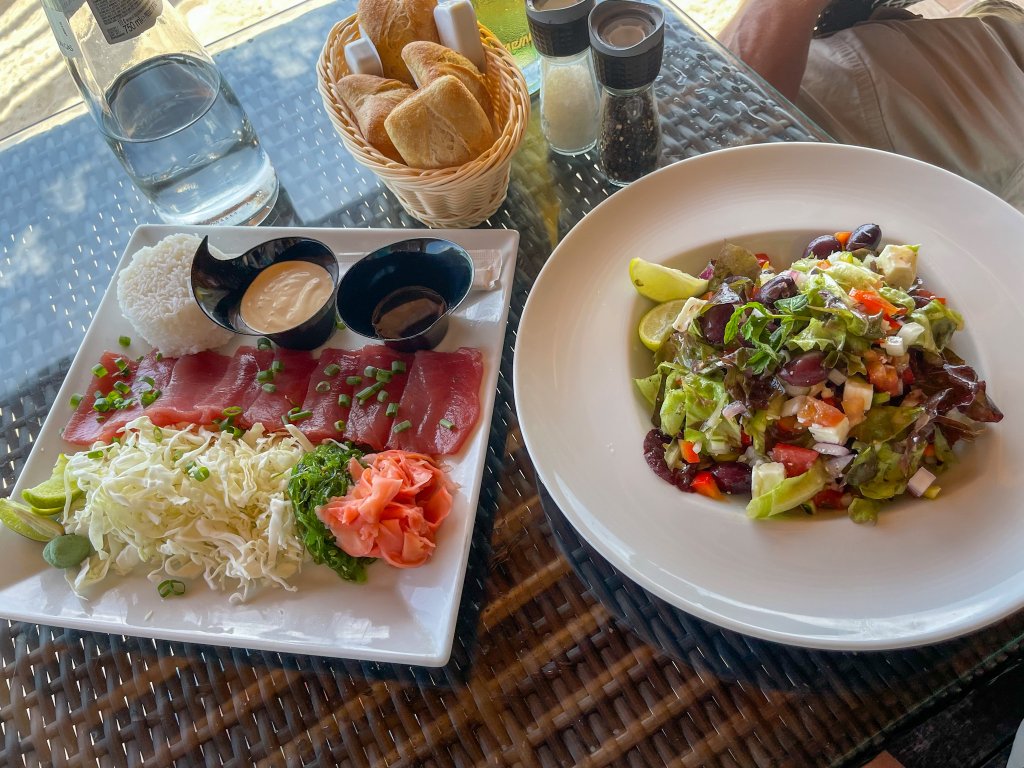 a picture of sashimi tuna and a salad on a restaurant table