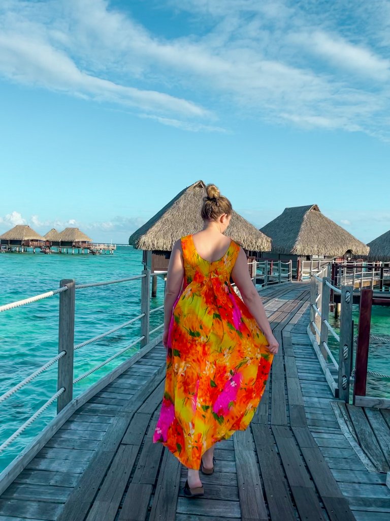 a women walking next to overwater bungalows in French Polynesia