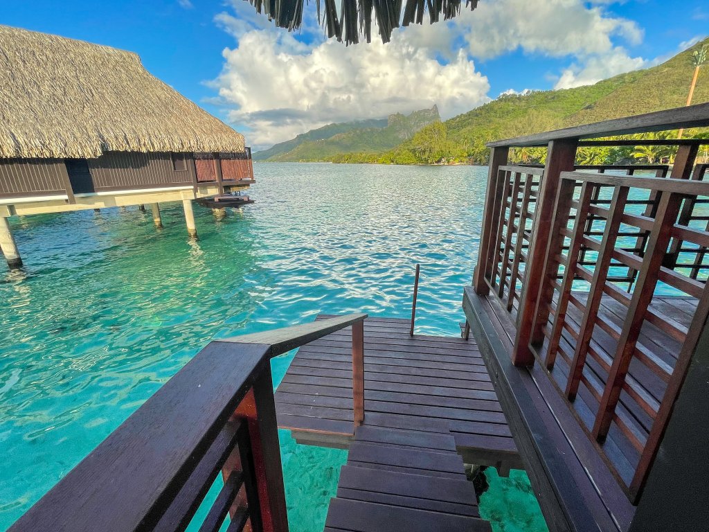 a set of wooden stairs going from a bungalow at the Hilton Moorea to the ocean with another bungalow in the background 