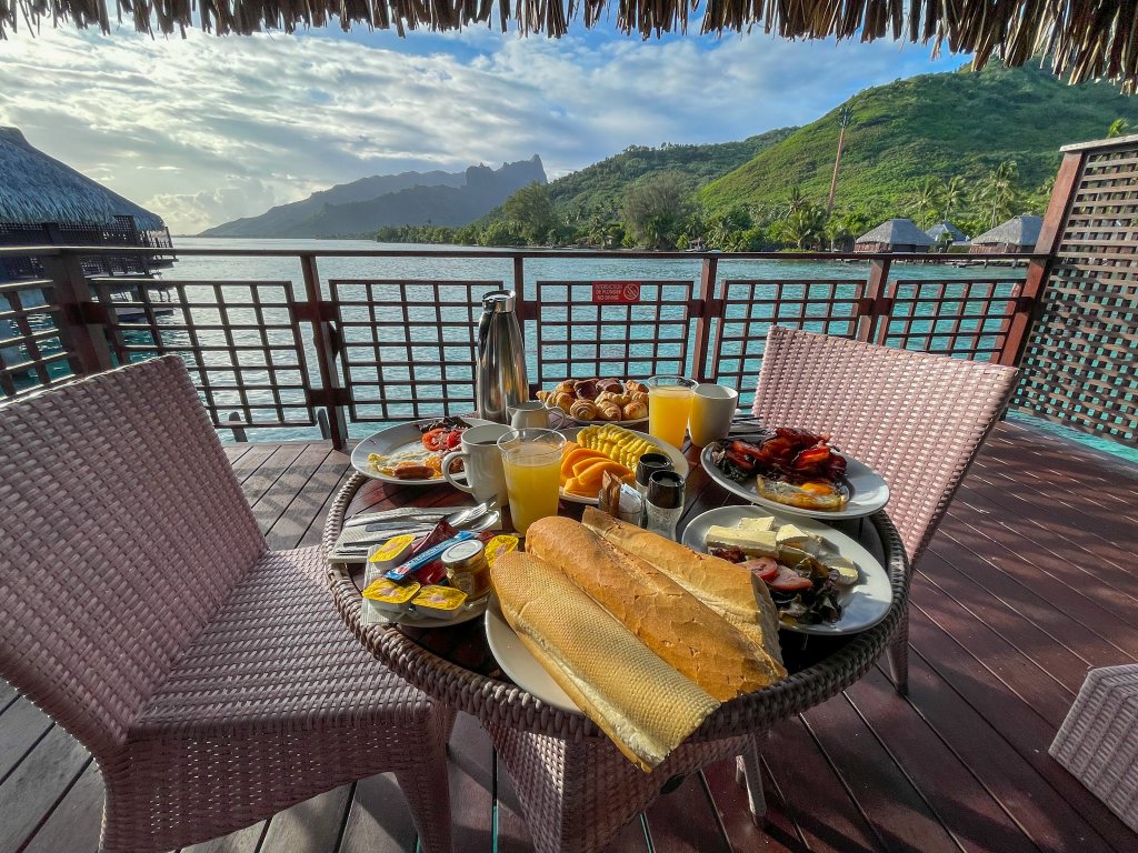 breakfast food on a table on a patio over looking the ocean