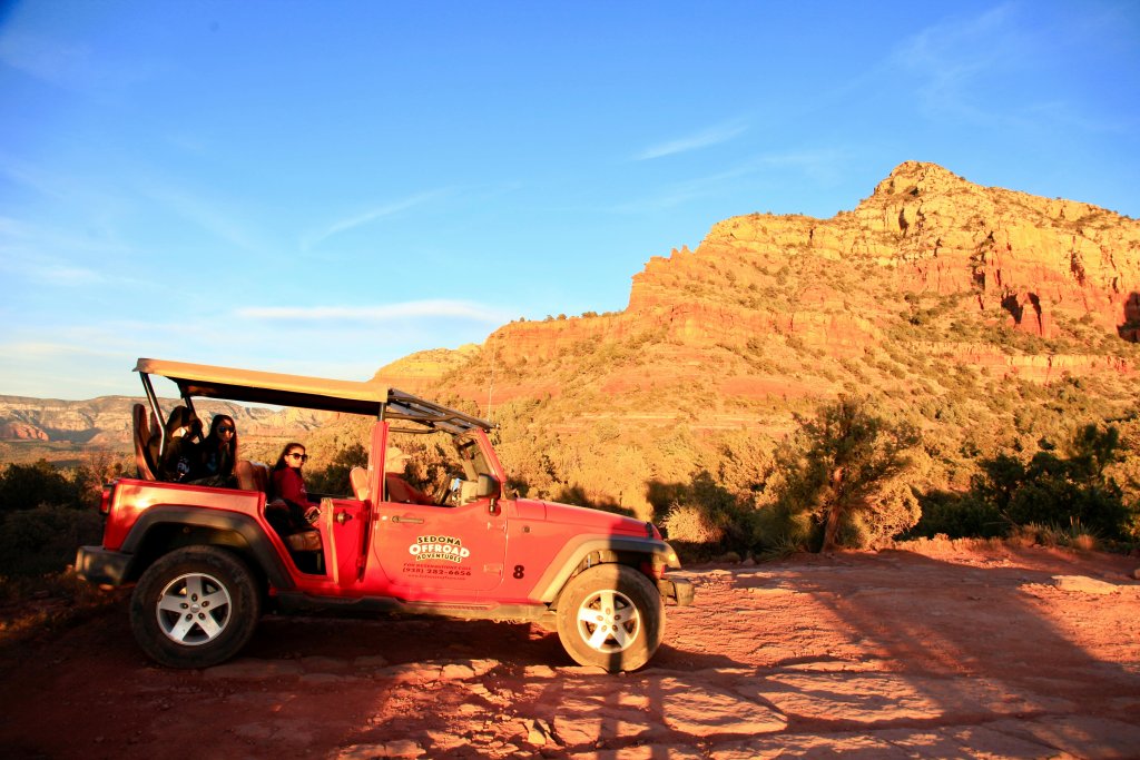 picture of a pink Jeep next to a red rock cliff in Sedona