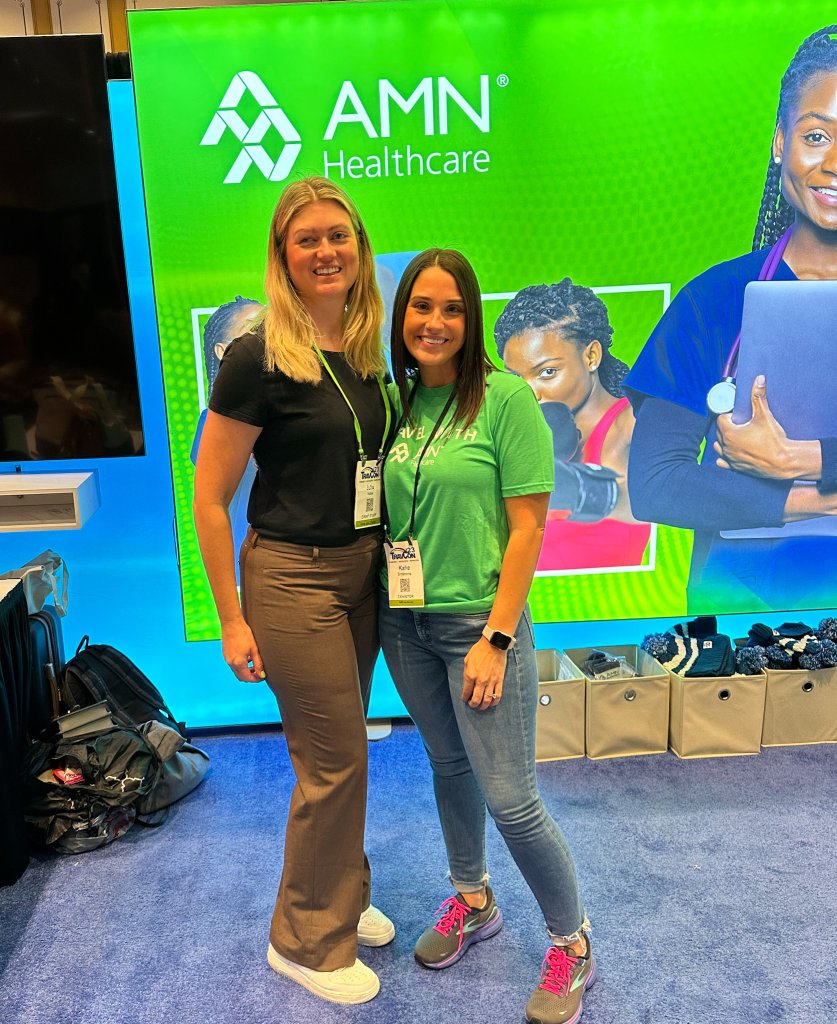 2 women standing in front of a sign that says AMN Healthcare