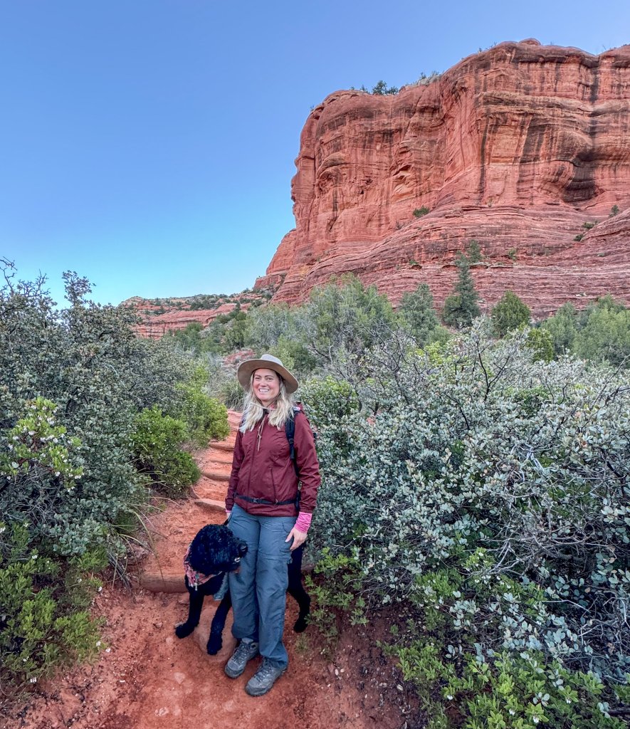 a women and a dog next to red rocks in Sedona