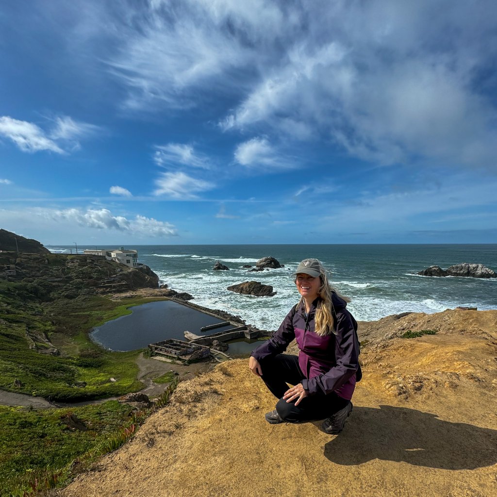 a women kneeling next to an ocean cliff