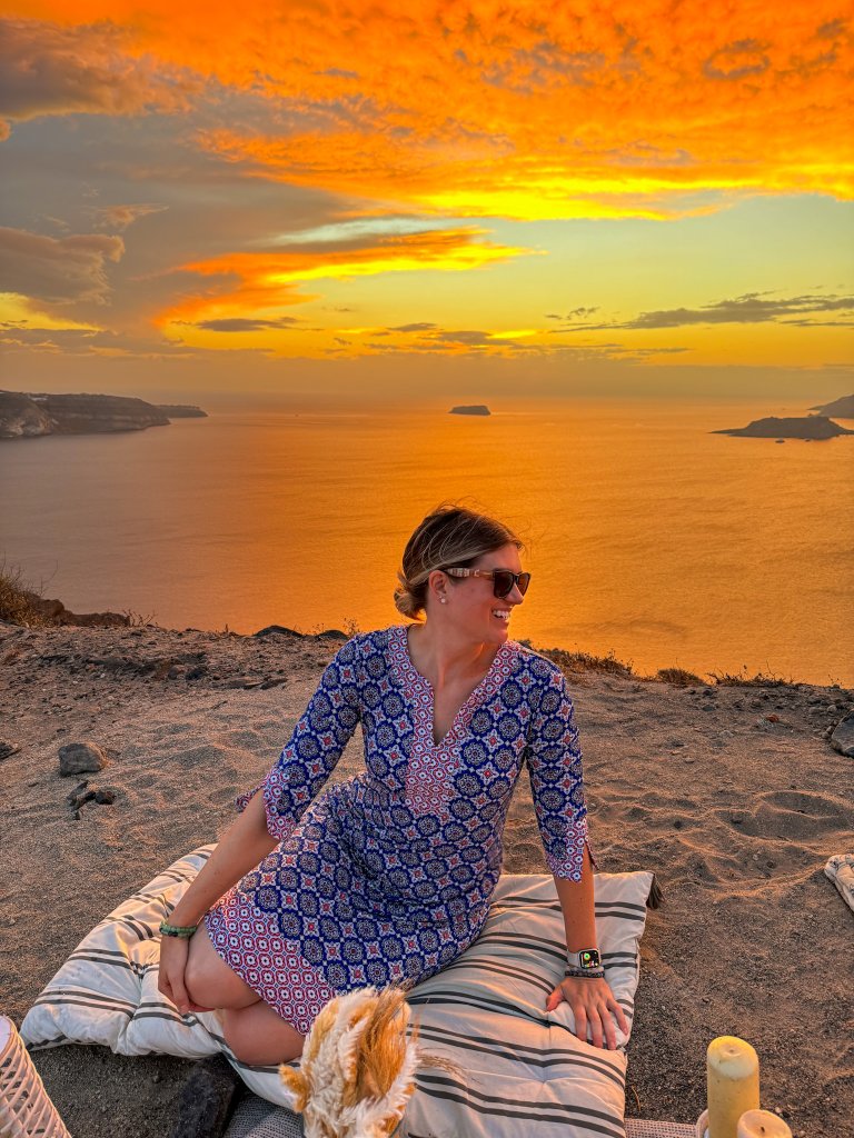 a women sitting on a cliff at sunset in Santorini