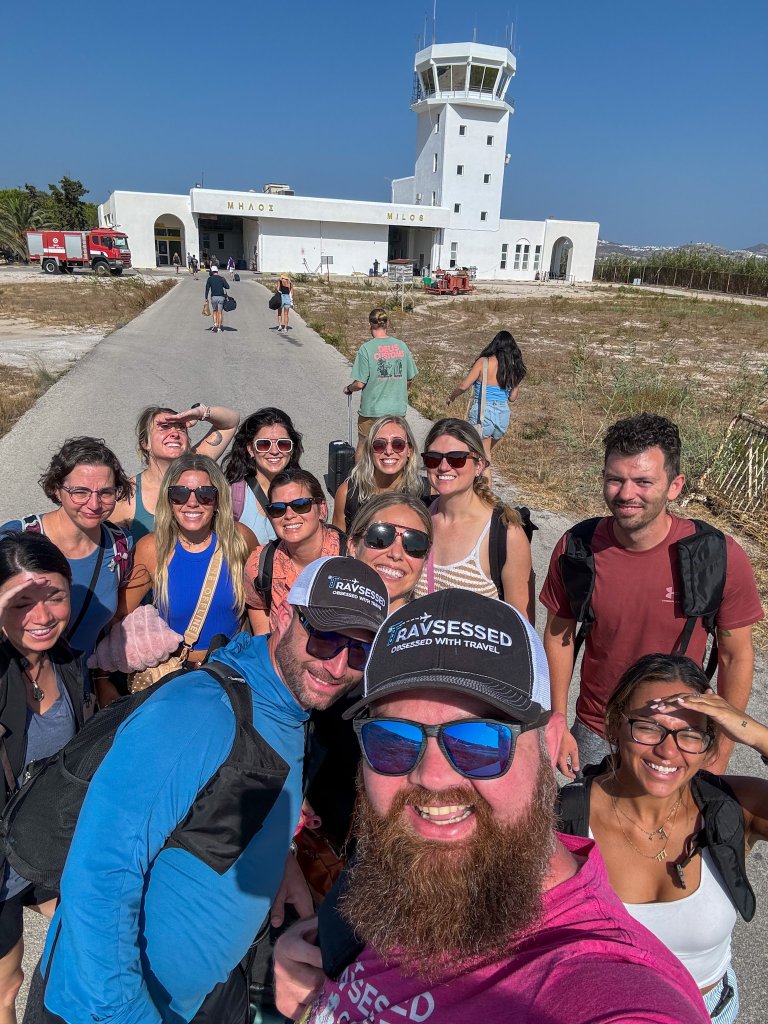 a group of people standing in front of an airport in Milos